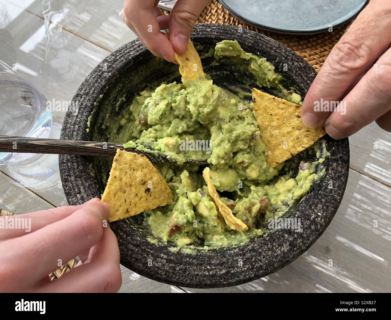 Dipping tortilla chips into guacamole - Smartphone Captured Stock Image Dipping tortilla chips into guacamole - Smartphone Captured Stock Image