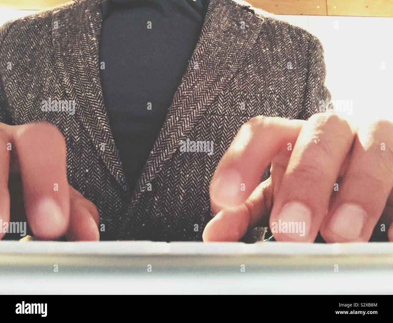A guy in a blazer typing on a keyboard. - Smartphone Captured Stock Image