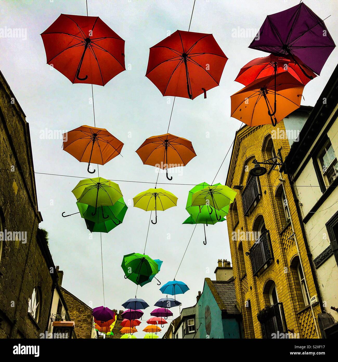 Colourful umbrellas fly above Palace Street in Caernarfon North Wales looking up Stock Photo