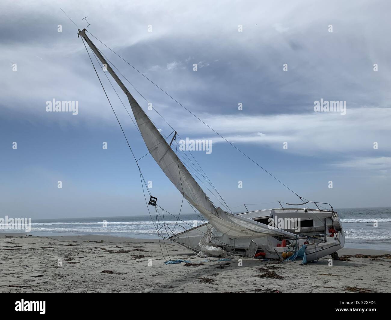 A small sailboat washed up on the shore of the Pacific Ocean. - Smartphone Captured Stock Image