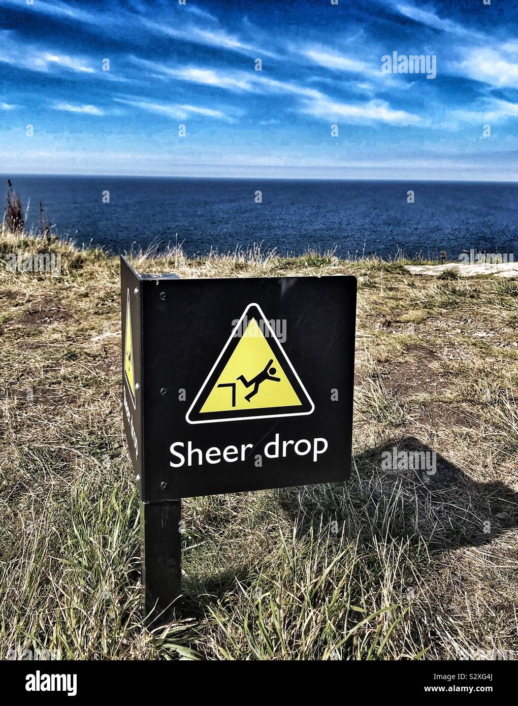 Sheer Drop Warning Sign At Cliff Edge - Tintagel Castle, Cornwall UK Stock Photo