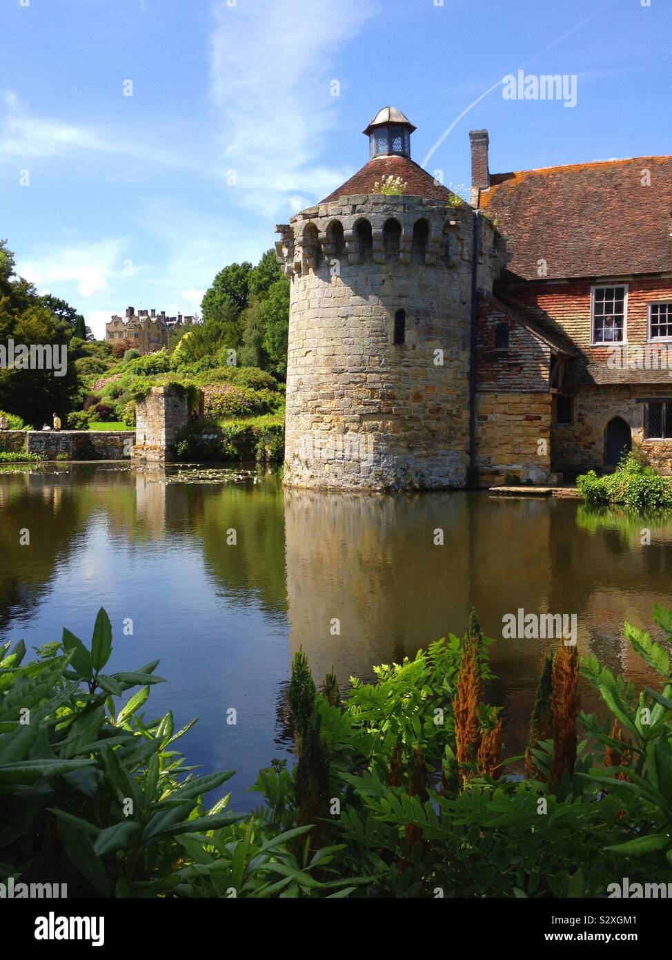The old castle at Scotney by the lake with the house behind Stock Photo
