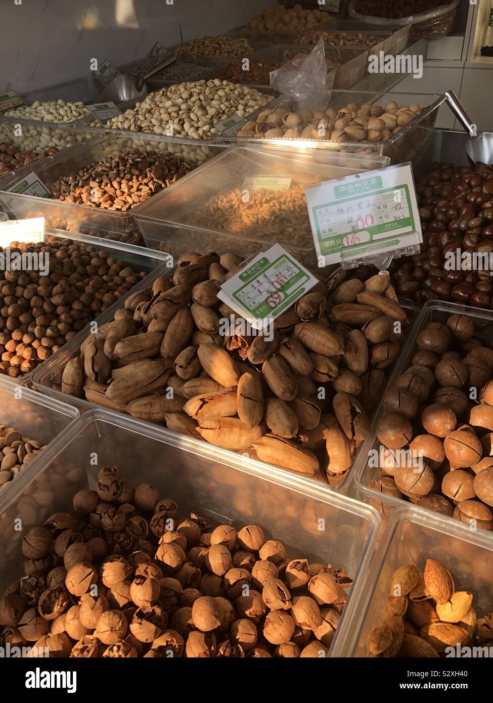 A selection of nuts for sale in late evening sunlight on a street stall in Beijing China. Stock Photo