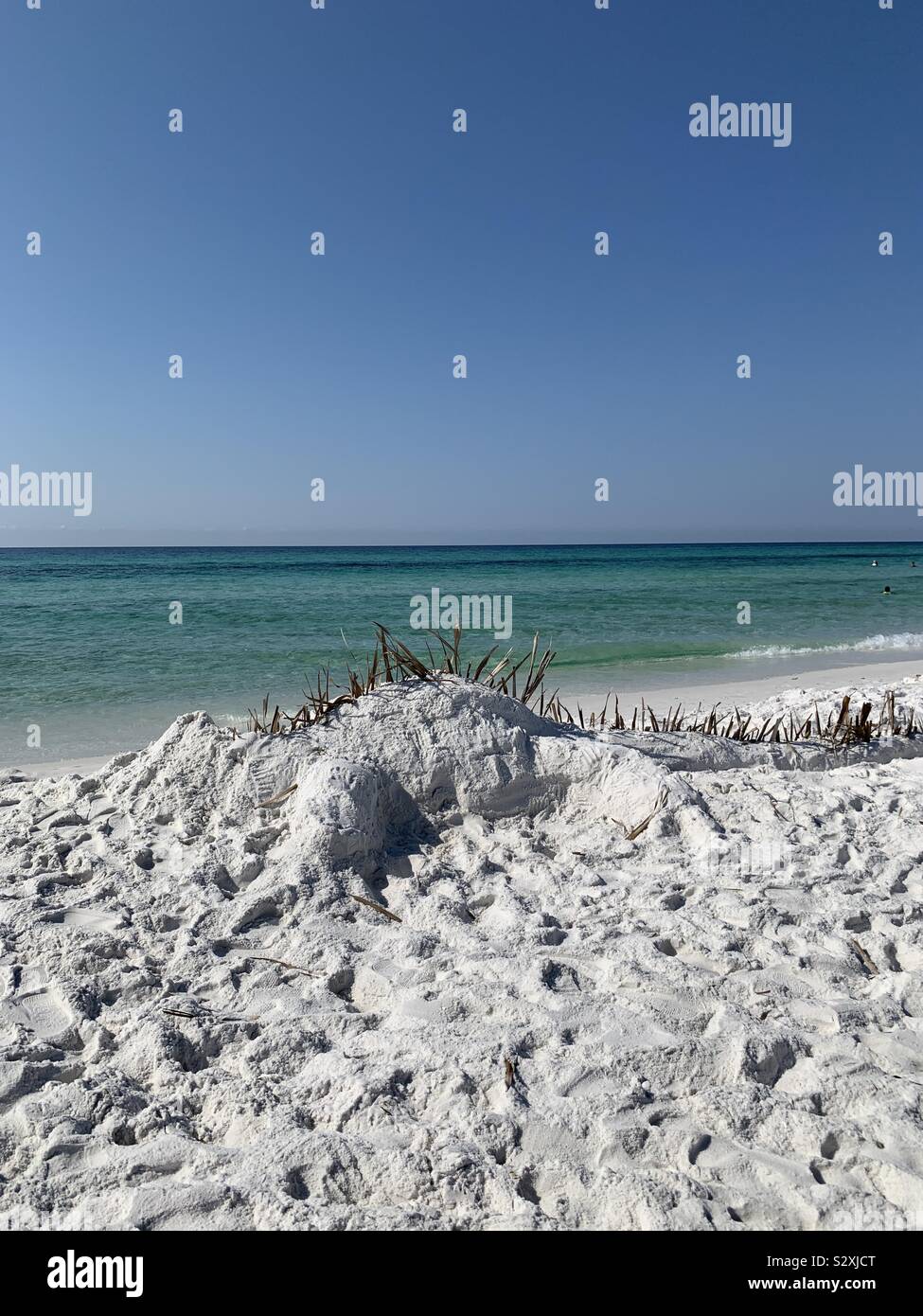 Dinosaur sandcastle on white sand beach Stock Photo
