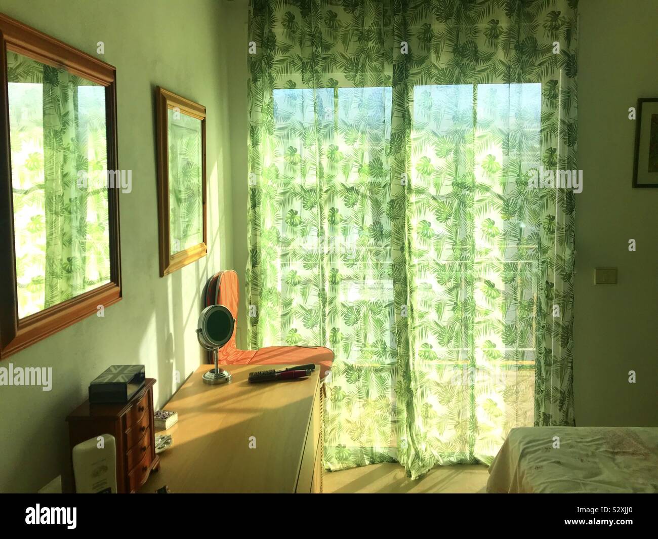 Green themed jungle patterned bedroom with sunlight pouring through the curtains - Smartphone Captured Stock Image