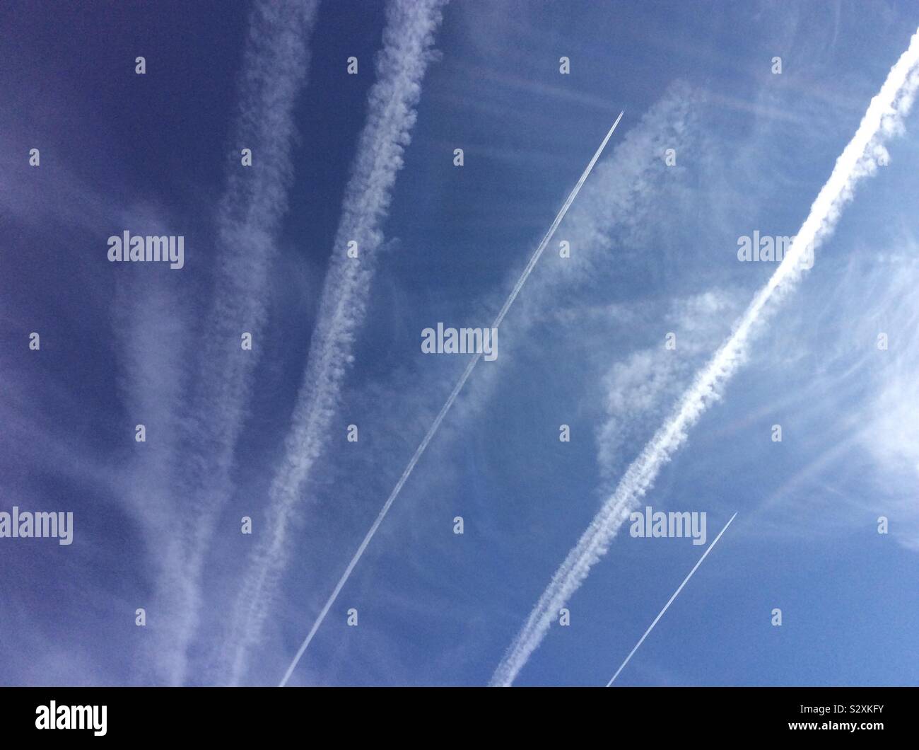 Many contrails or vapour trails in the sky from several jet planes in the sky Stock Photo