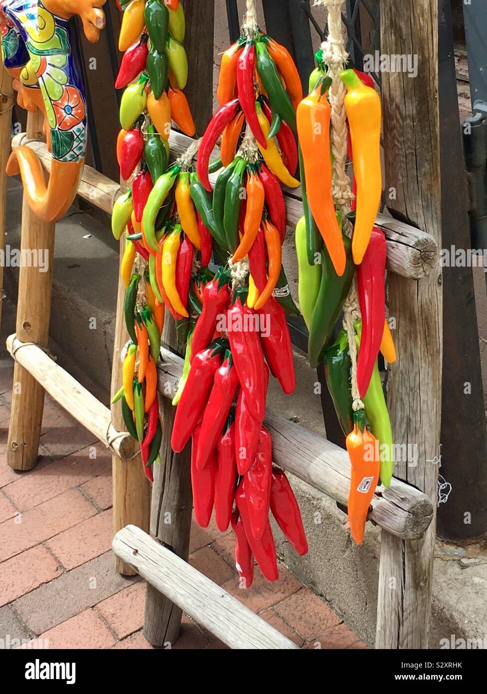 Brightly colored plastic peppers hanging on a ladder Stock Photo