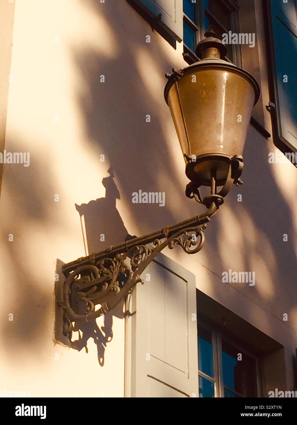 Street lantern attached to white wall in shades of brown Stock Photo