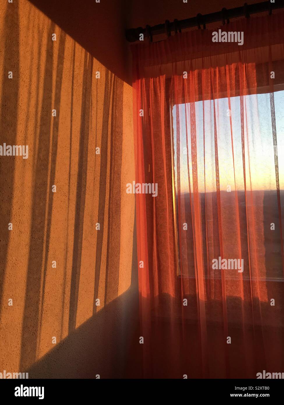 Sunrise through an orange curtain Stock Photo