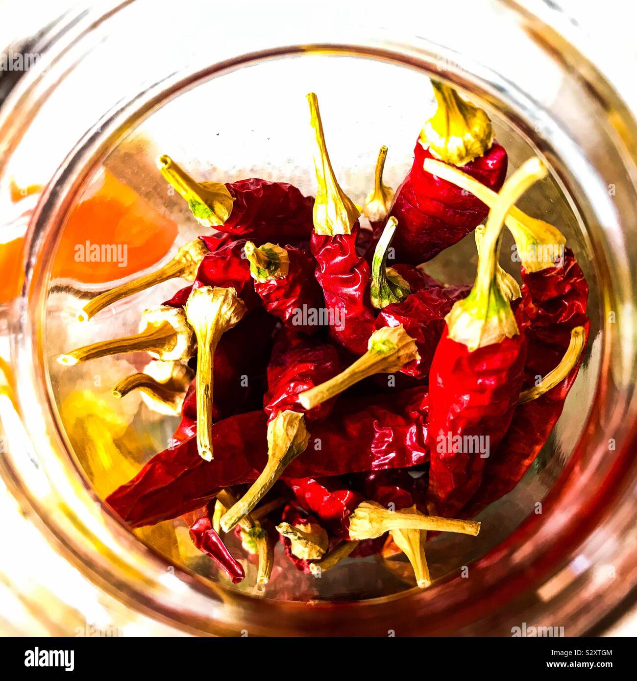 Dried red Cayenne chilli peppers stored in an open topped Kilner jar on kitchen work surface Stock Photo