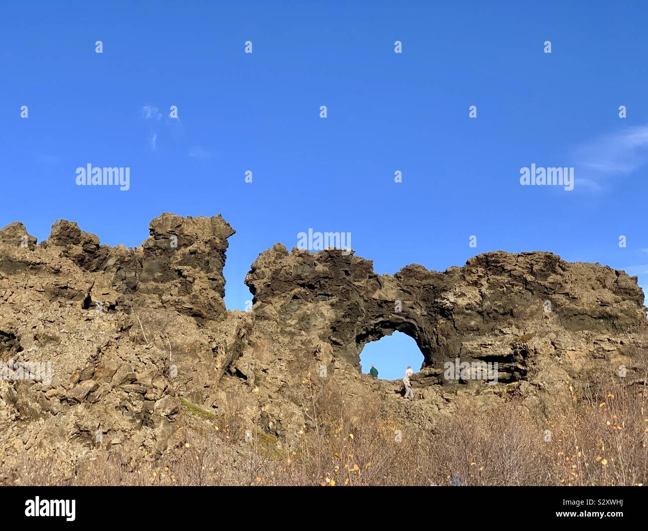 Dimmuborgir lava field Iceland - September 2019: Lava field with lots of marked hiking trails. Tourists walk up to and through the hole. Stock Photo