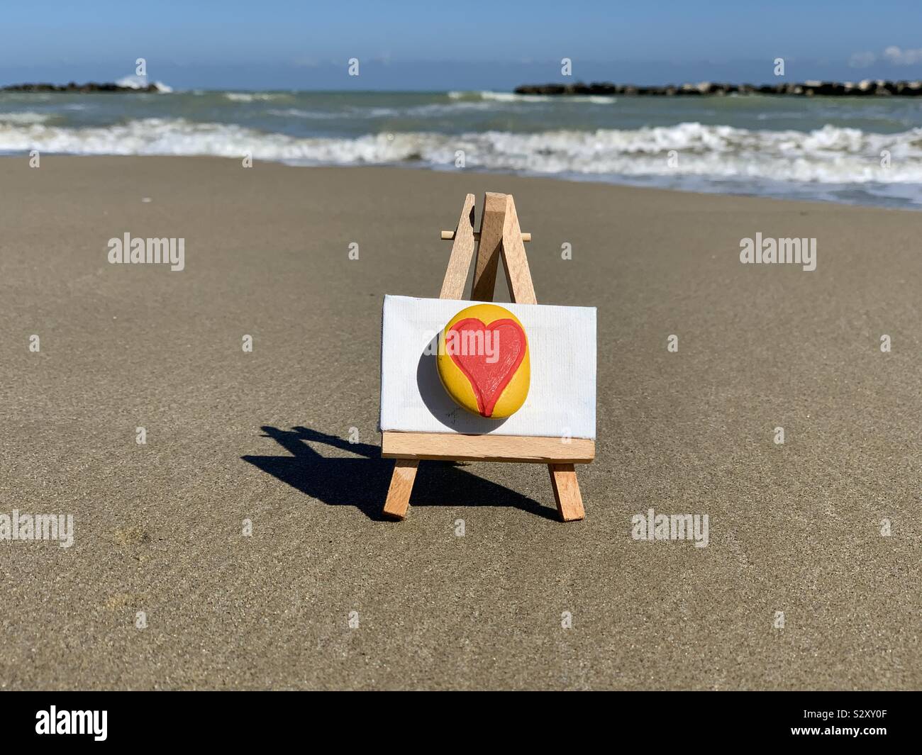 Love message with a colored heart on a stone with beach background Stock Photo