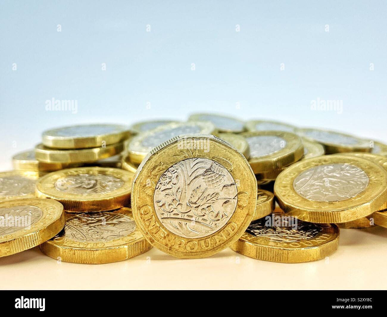 One pound coin on edge with pile of coins in the background Stock Photo