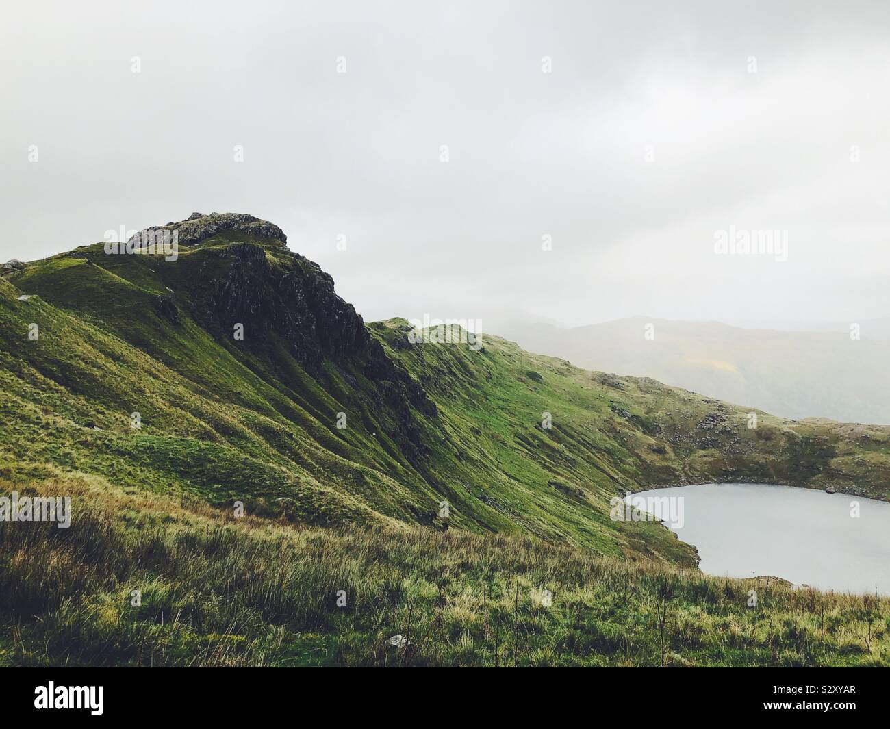 View of mountain cliff face over lake Stock Photo