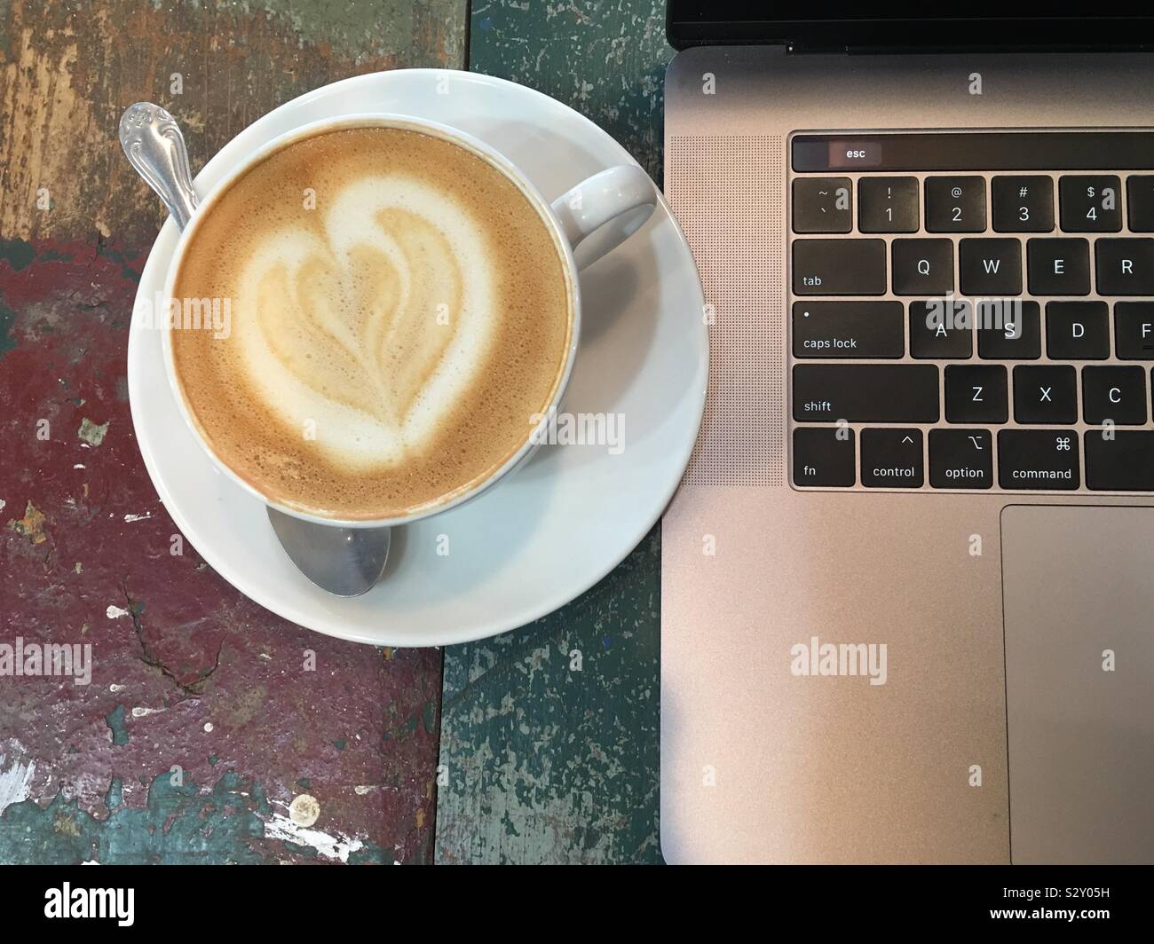 Foamy espresso with a heart and a laptop working at a coffee shop self employed freelance economy concept. Stock Photo