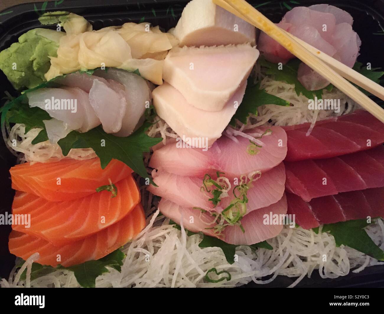 Close up of an assorted sashimi entrée delivery meal with wooden chopsticks - Smartphone Captured Stock Image