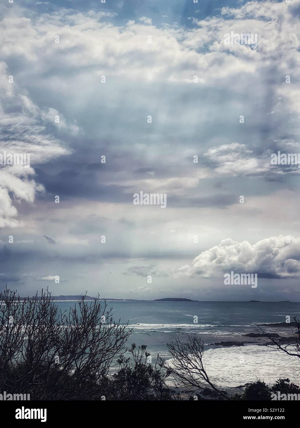 Stormy day by the sea, sunlight shining through the clouds, blue Pacific Ocean - Smartphone Captured Stock Image Stormy day by the sea, sunlight shining through the clouds, blue Pacific Ocean - Smartphone Captured Stock Image