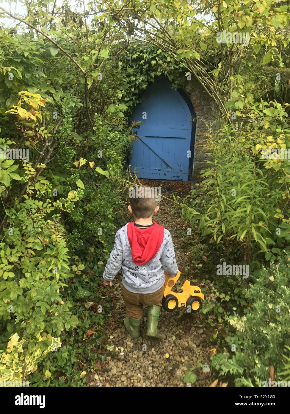 Toddler walks to a blue gate Stock Photo