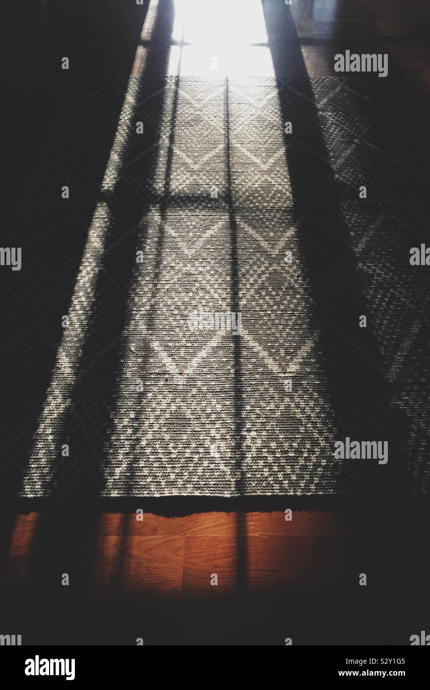 Light and shadows on a diamond patterned area rug Stock Photo