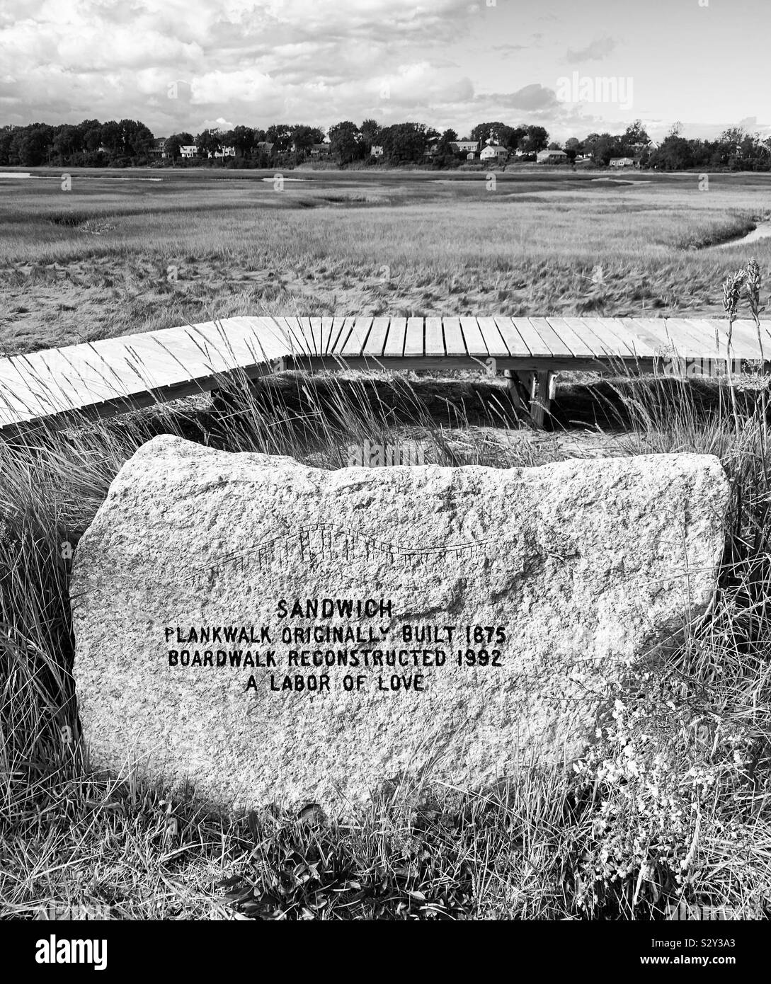 Inscription on rock reads “Sandwich Plankwalk originally built 1875. Boardwalk reconstructed 1992. A labor of love.” Sandwich, Cape Cod, Massachusetts, United States. - Smartphone Captured Stock Image