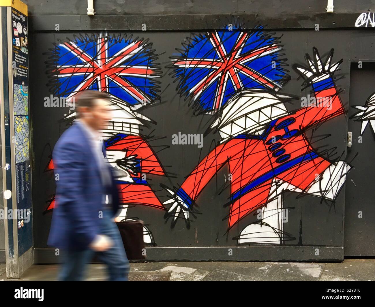 Blurred man walks by a street art mural by Nathan Bowen in London, England UK - Smartphone Captured Stock Image