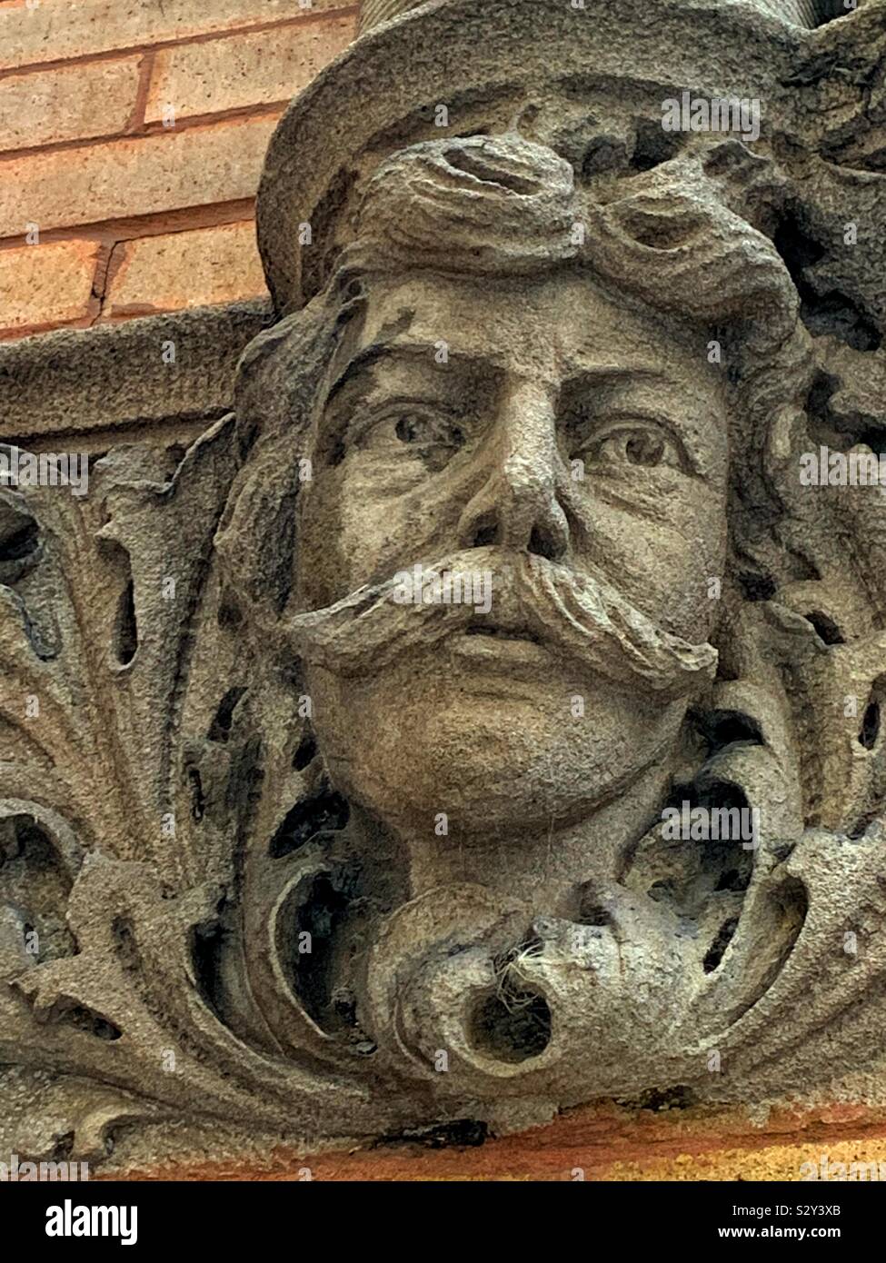 Stone sculpture of a mustached adult man looking off into the middle distance. - Smartphone Captured Stock Image