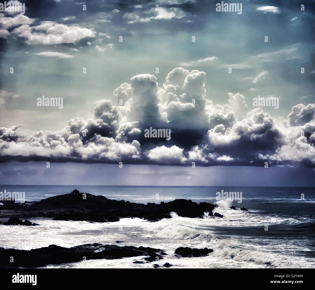 Low hanging finger shaped storm clouds hovering, floating in the sky above the ocean near the beach - Smartphone Captured Stock Image