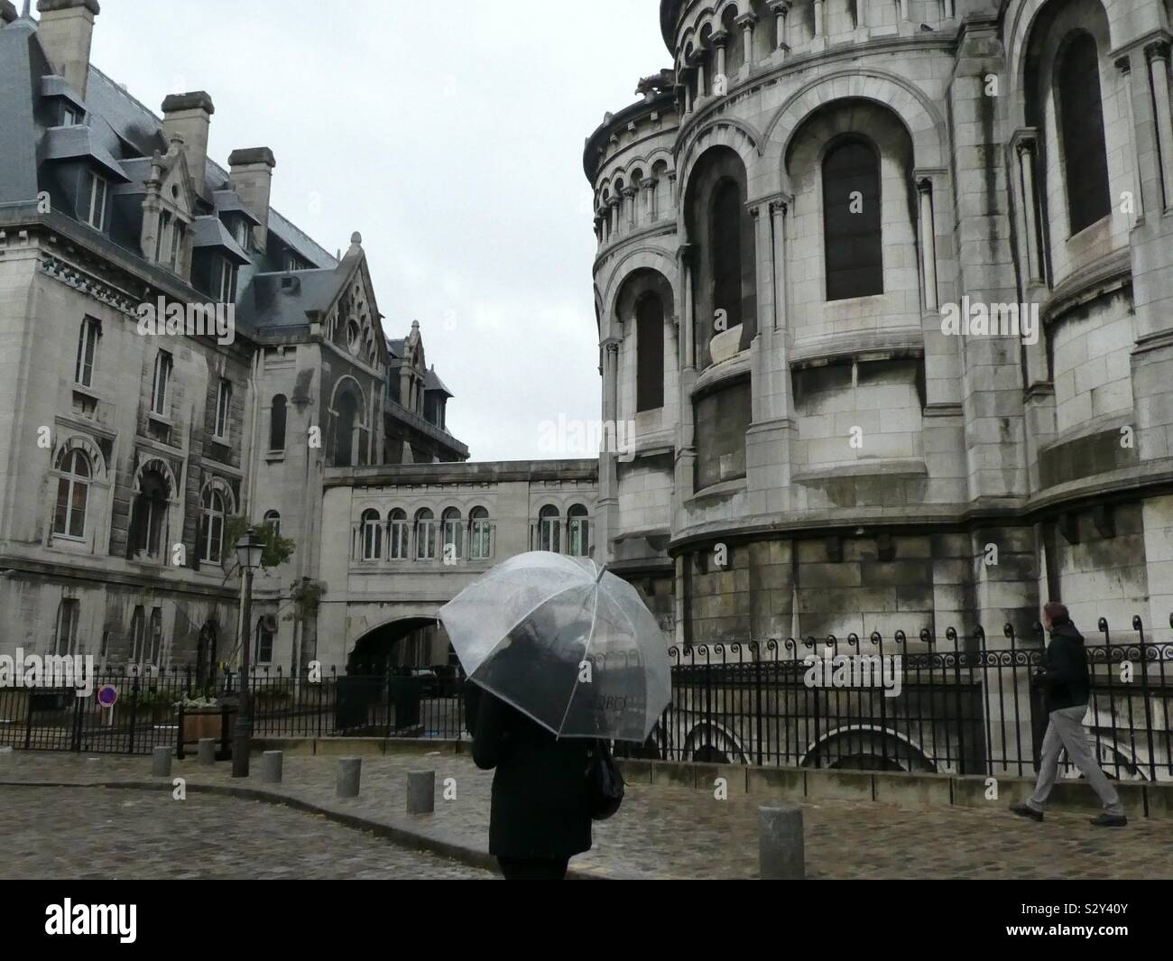 Walking in the rain with an umbrella on the streets of Paris past beautiful grand buildings Stock Photo