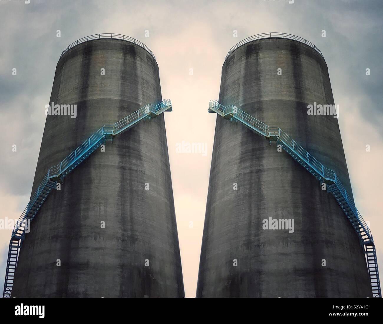 Two silos with metal stairs wrapping around their exteriors - Smartphone Captured Stock Image