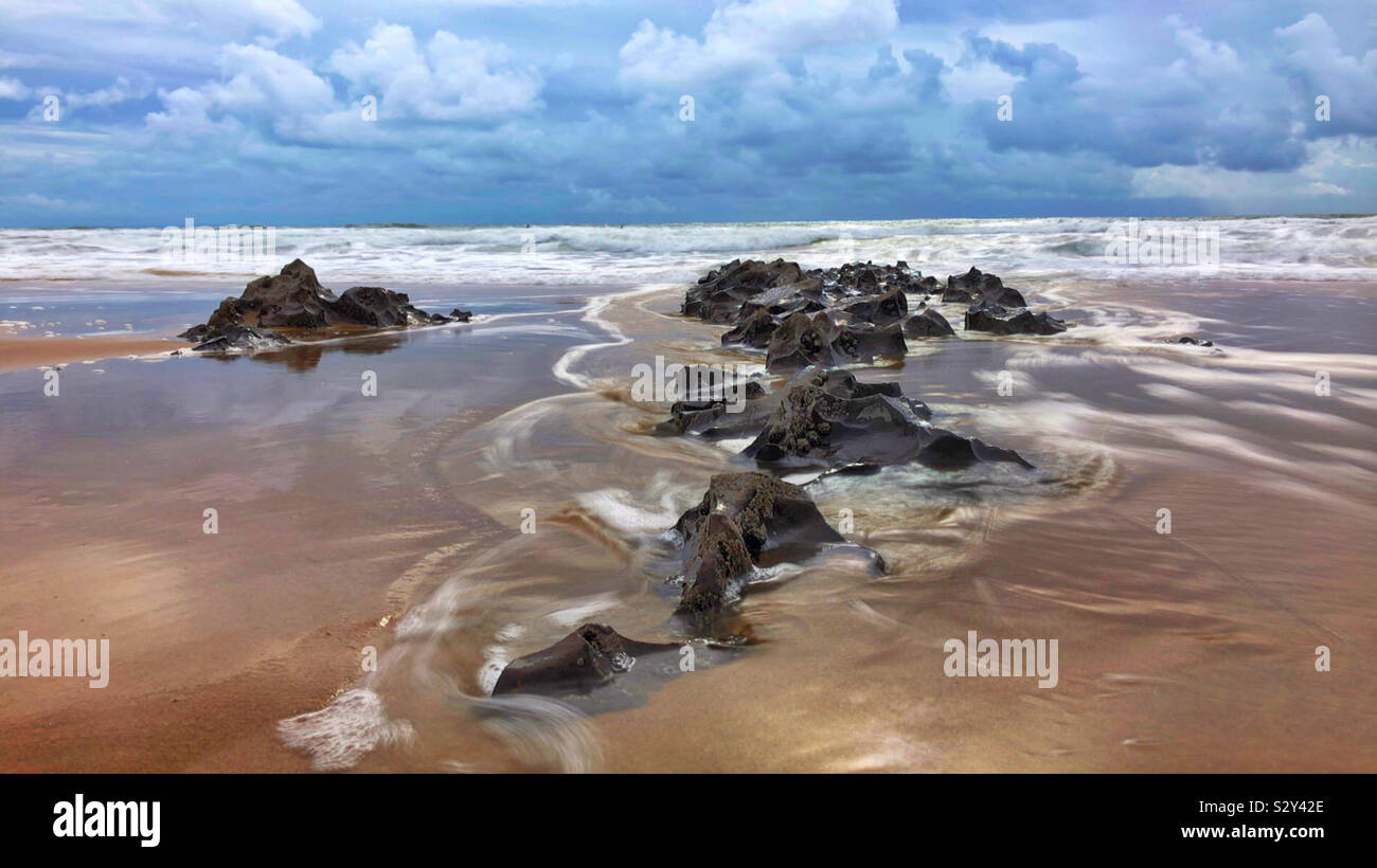 Rocks and flowing water on a Welsh surf beach, Gower, Swansea, Wales. Stock Photo