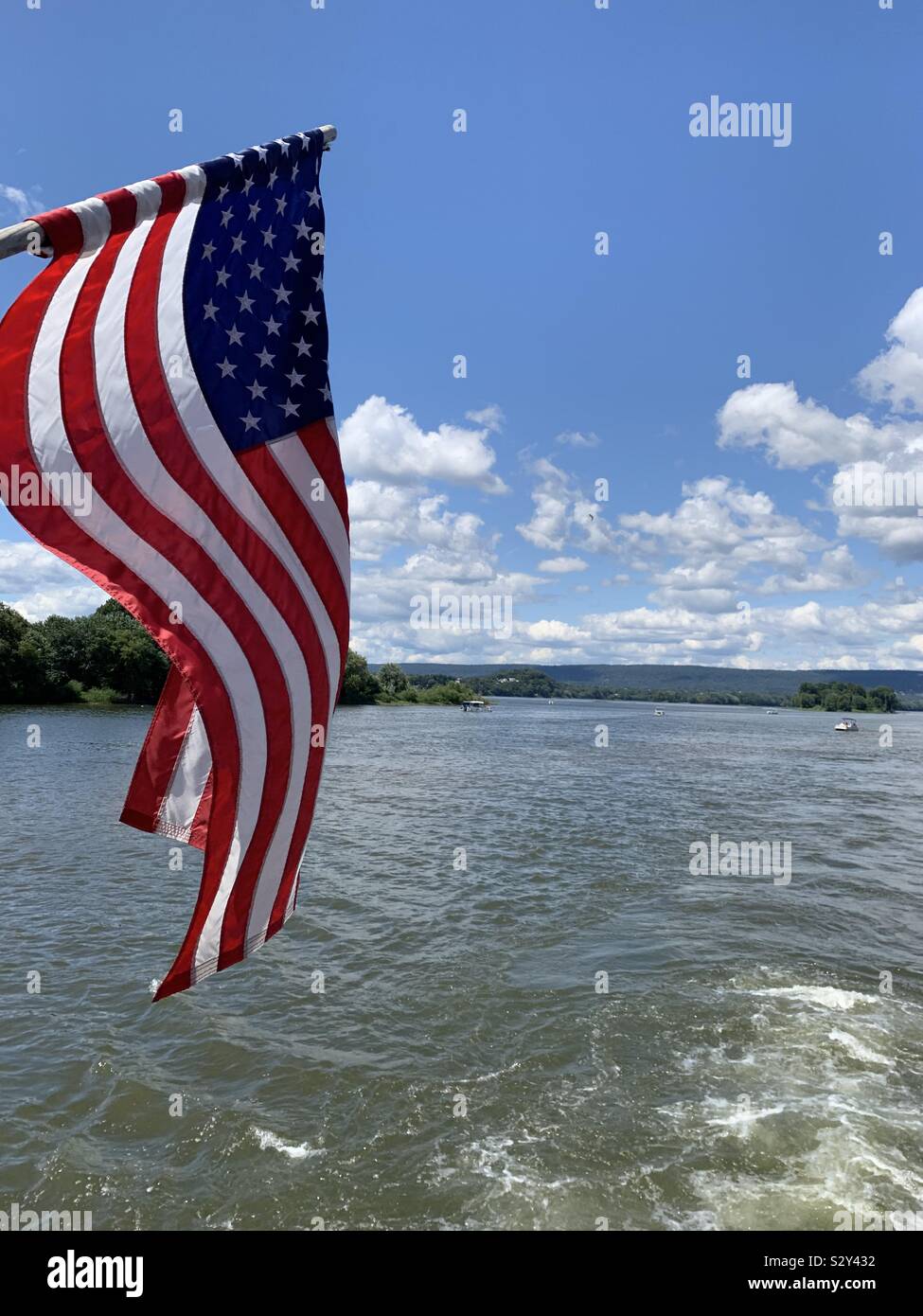 American flag blowing in the wind off the back of a boat on the river. Stock Photo
