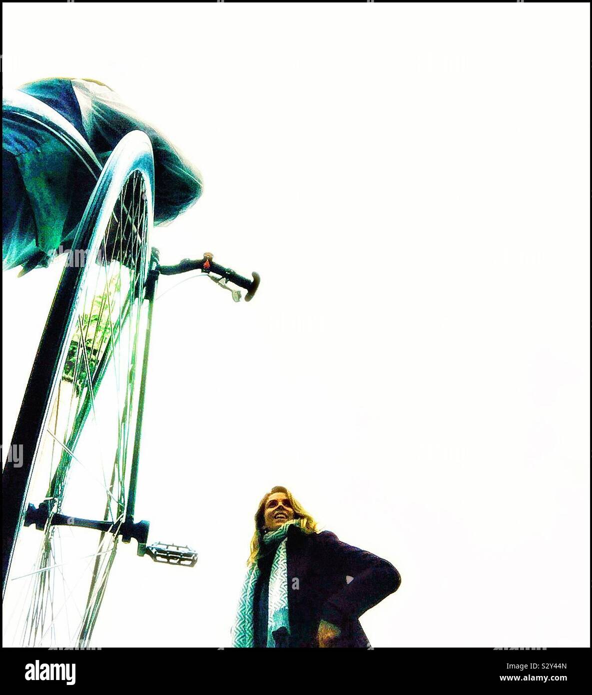 A young woman smiles at a Penny Farthing bike. - Smartphone Captured Stock Image