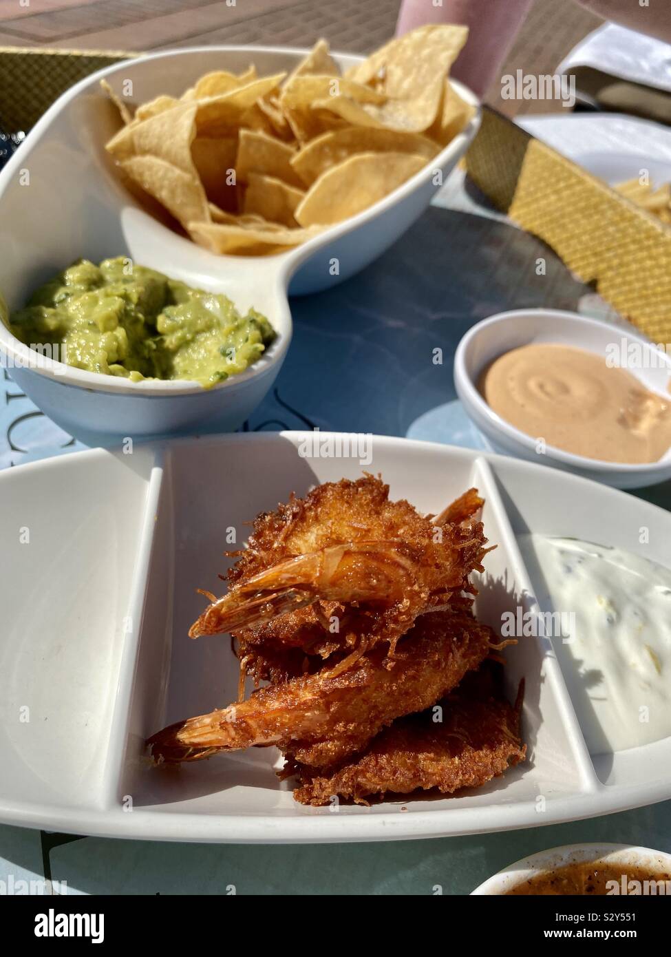 Poolside appetizers of coconut fried shrimp, chips, guacamole, and other dips - Smartphone Captured Stock Image Poolside appetizers of coconut fried shrimp, chips, guacamole, and other dips - Smartphone Captured Stock Image