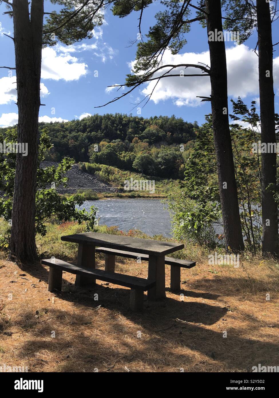 A stone picnic table beside the lake water - Smartphone Captured Stock Image