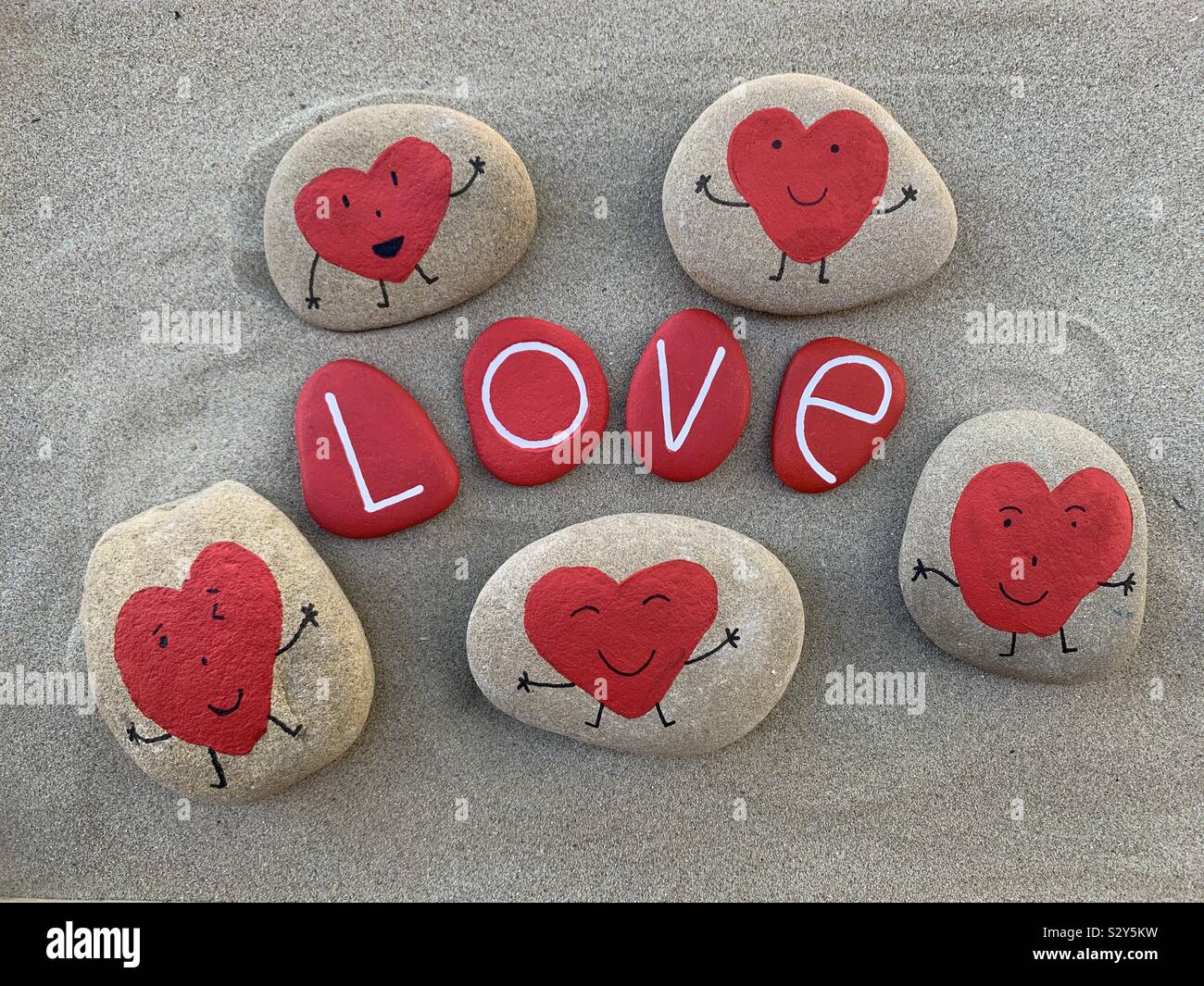 Love message with creative painted stones over brown sand Stock Photo