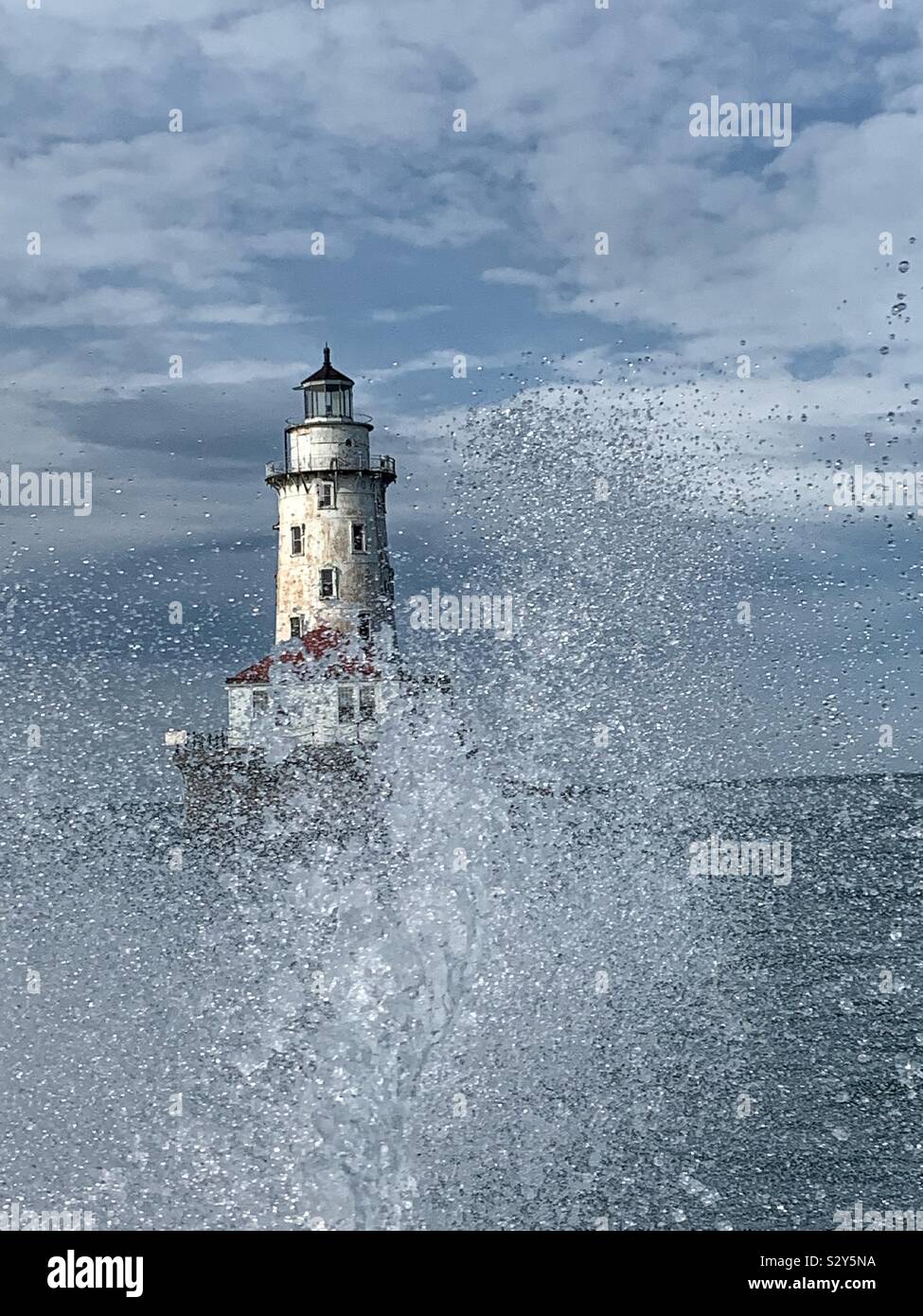 Water spray with an old lighthouse in the background. - Smartphone Captured Stock Image