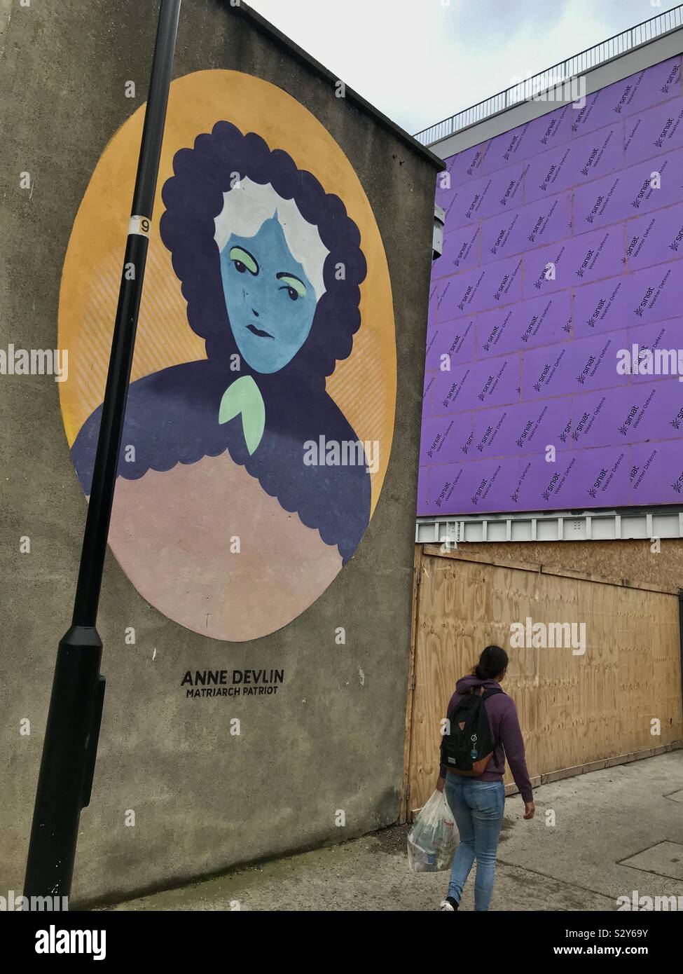 A woman walks past a mural of the Irish Rebel, Anne Devlin, in the Liberties area of Dublin, Ireland. Stock Photo