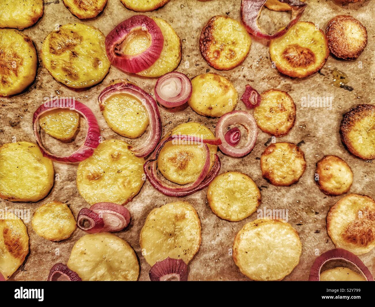 Freshly cooked homemade sauté potatoes with red onions on baking tray Stock Photo