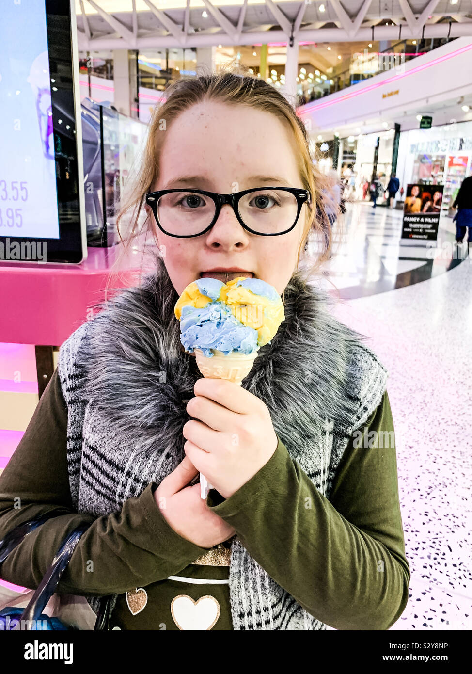 Young girl licking an ice cream cone in a shopping centre Stock Photo