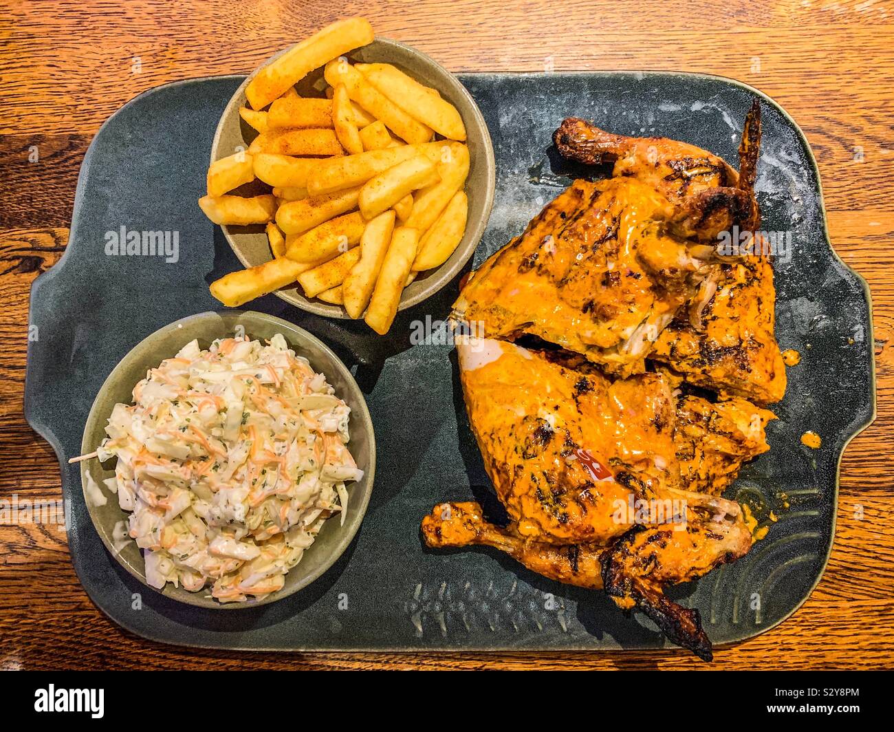 Nando’s hot chicken and chips and coleslaw on slate plate Stock Photo