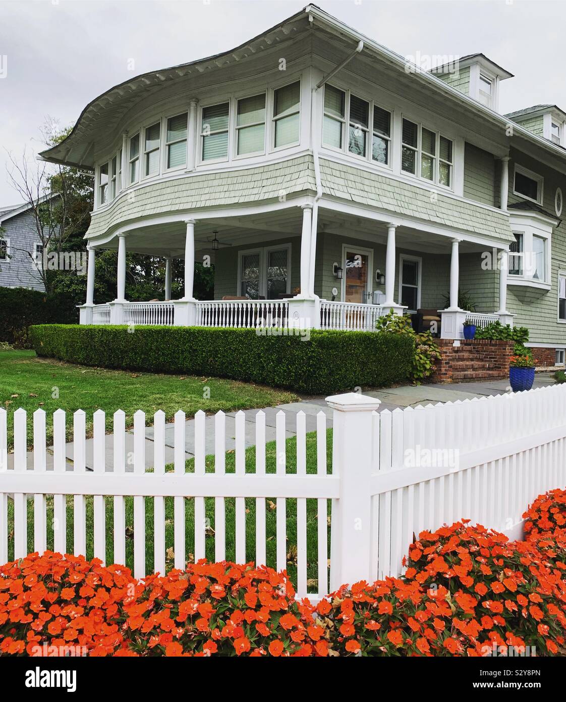 Orange flowers and a white fence in front of a home in Allenhurst, Monmouth County, New Jersey, United States - Smartphone Captured Stock Image
