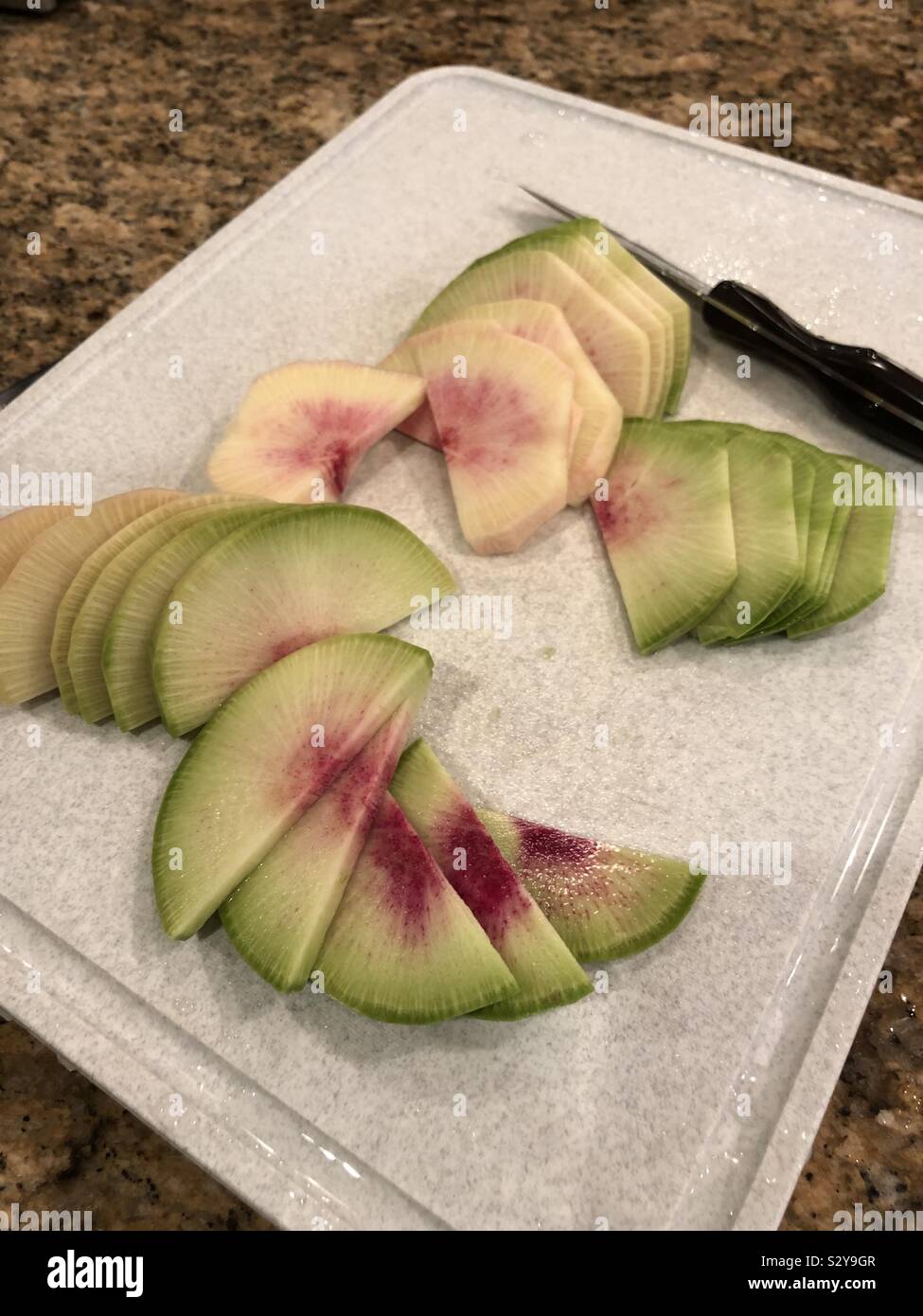Watermelon Radish freshly sliced with knife on a cutting board - Smartphone Captured Stock Image