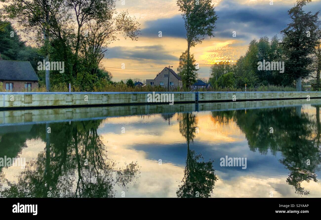 Colorful painterly autumn sky reflected in the water of a river or canal flowing through a natural Countryside area - Smartphone Captured Stock Image