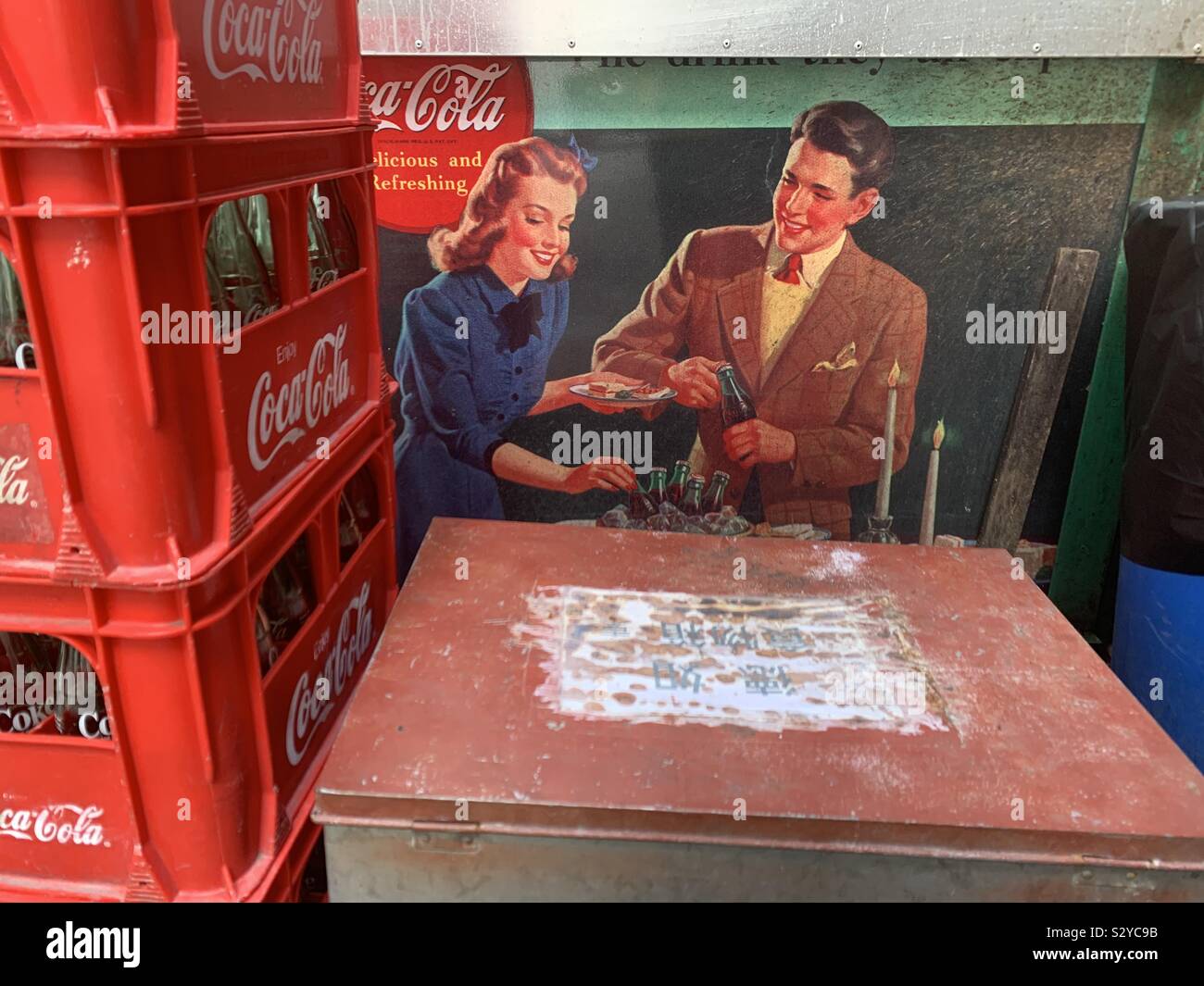 Coca Cola bottles by an old advertisement for Coca Cola in Hong Kong. Stock Photo