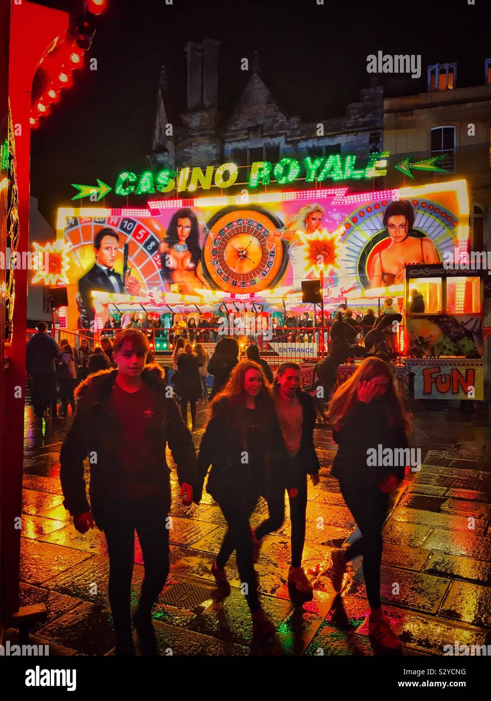 All the fun of the fair. A night time view of an autumn fair in a town somewhere in England. Wet pavements & bright lights add to the atmosphere. Photo © COLIN HOSKINS. - Smartphone Captured Stock Image