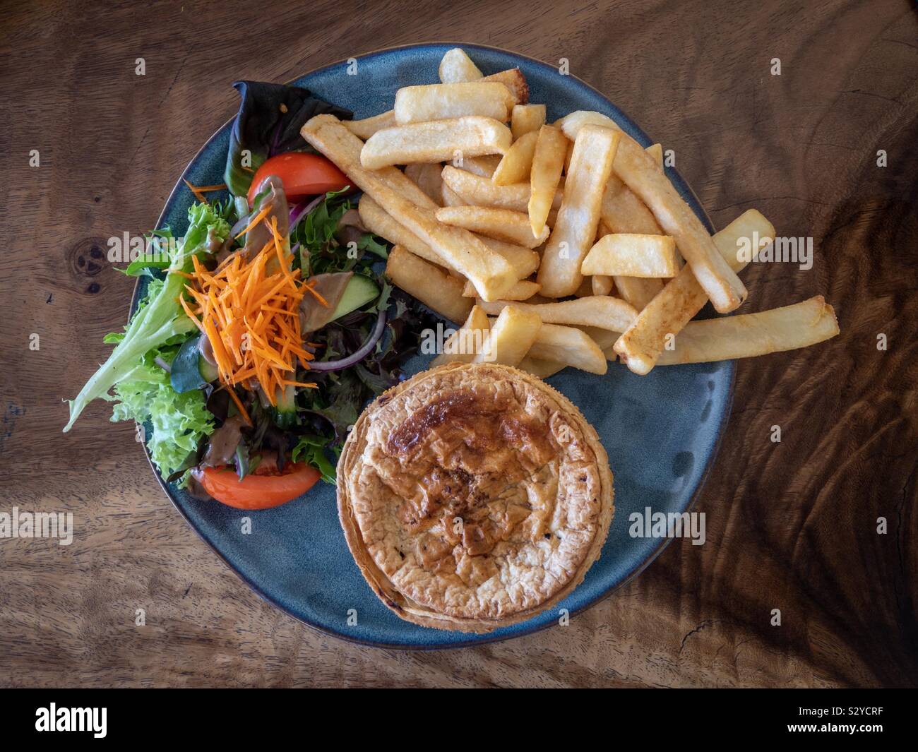 Typical Australian pub meal: a meat pie with salad and fries. Stock Photo