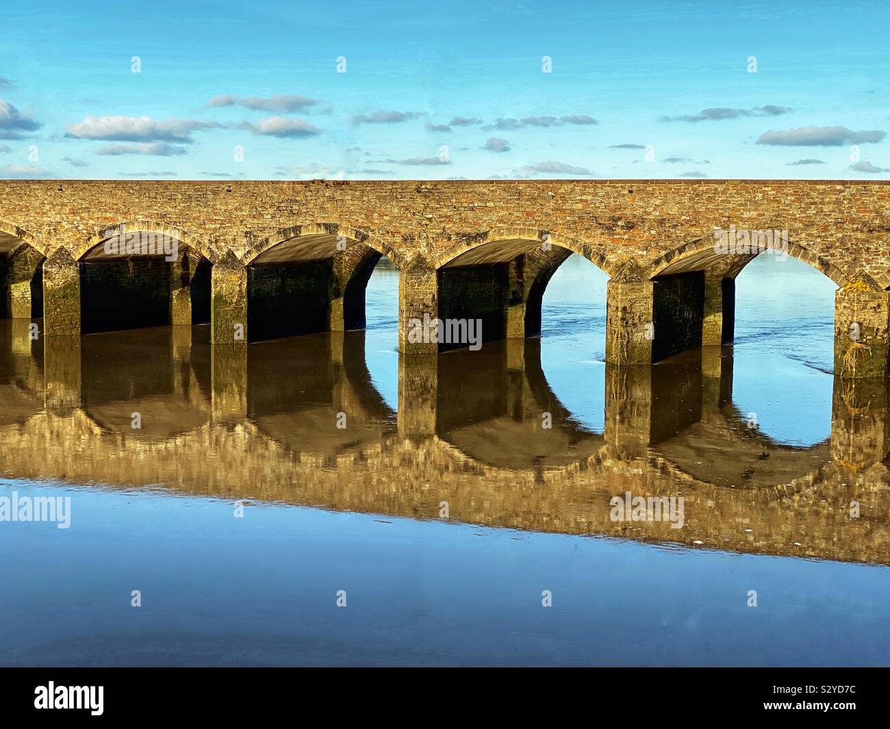 Arched bridge in early morning light reflected in still water Stock Photo
