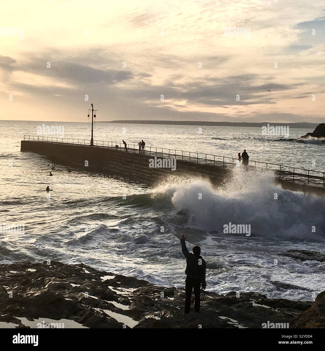 Waves hit the harbour wall at Porthleven, Cornwall, UK as the sun sets - Smartphone Captured Stock Image