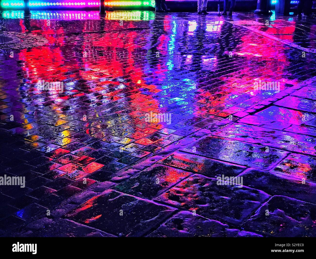 Colourful lights reflected on a wet pavement area. At least there is some good things to be said for rain at night! An image with potentially multiple uses. - Smartphone Captured Stock Image