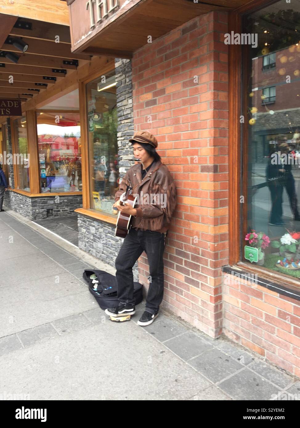 Visit town of Banff, Alberta, Canada, Banff National Park,street photography, Street musician, busker, guitar, harmonica - Smartphone Captured Stock Image